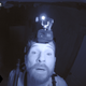 A man with a camera on his head, illuminated in night vision.